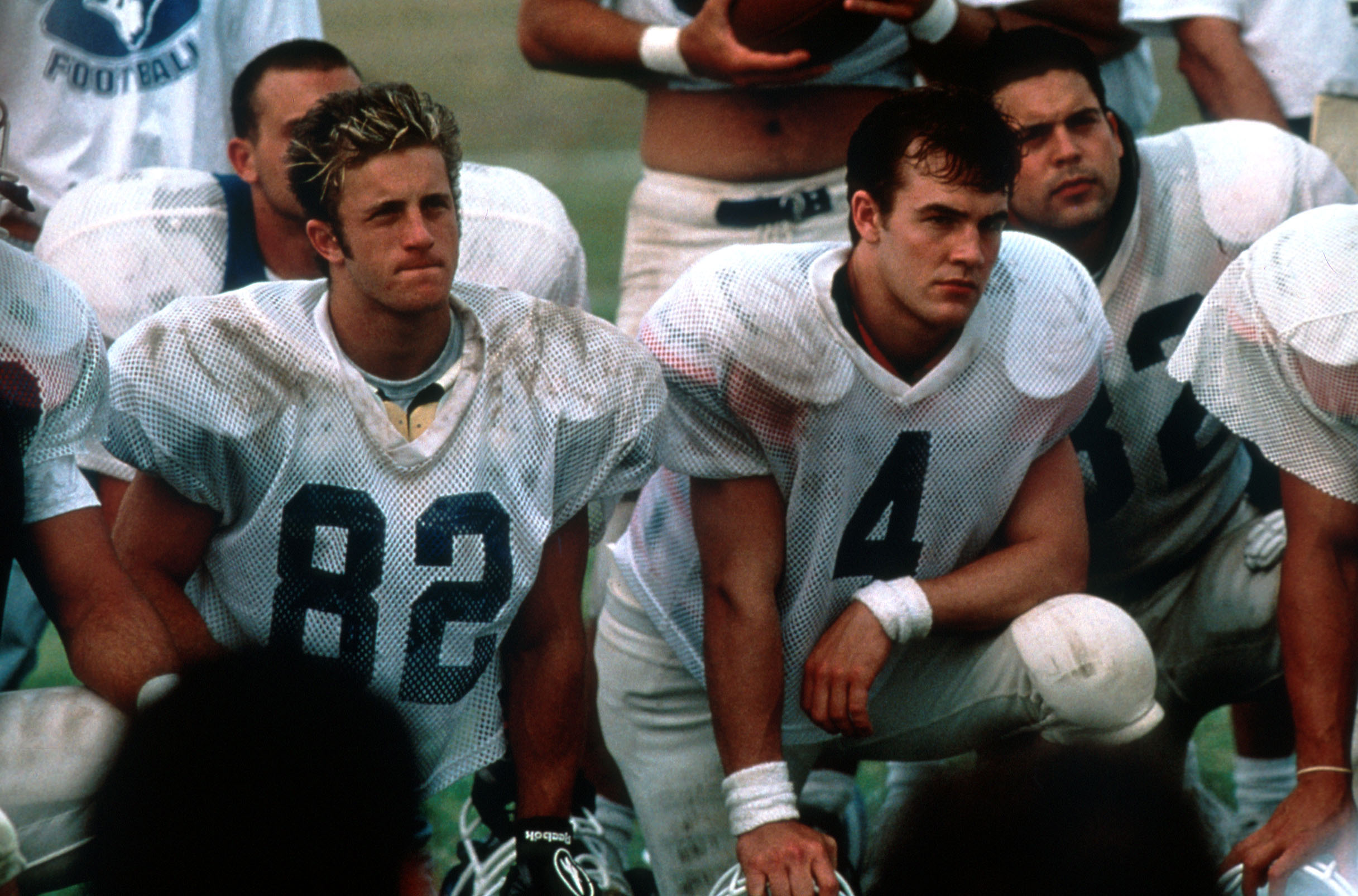 James Van Der Beek stars in 'Varsity Blues' as a young football player kneeling on a field with other athletes