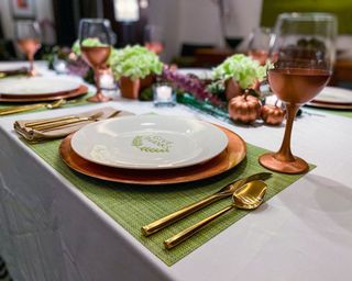 Thanksgiving tablescape with copper chargers, pumpkins, wine glasses and centerpiece