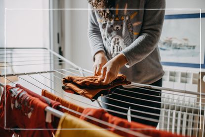 Mid-section of woman hanging laundry on a clothes airer at home