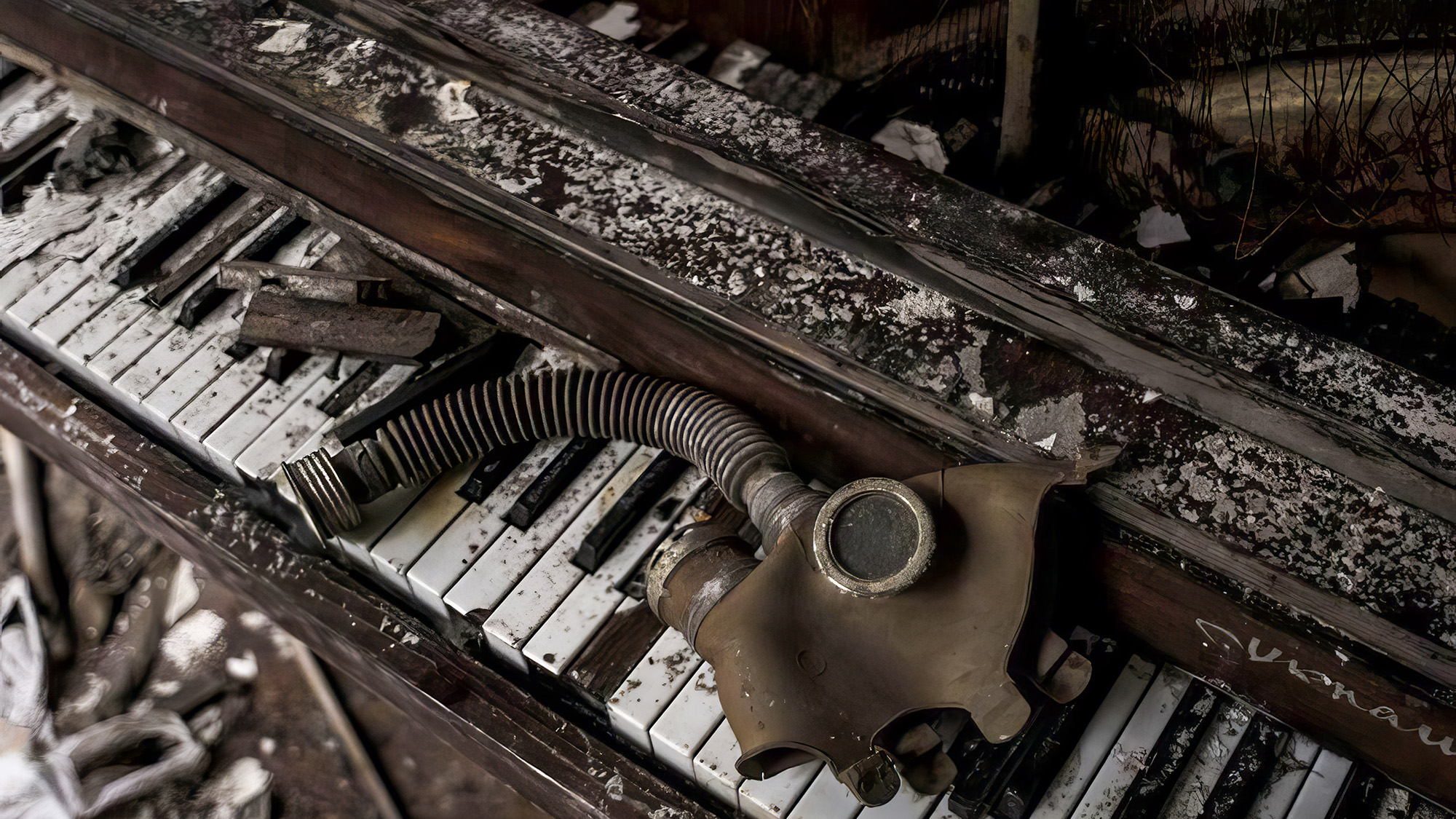 A brown rusty gas mask sits on top of a broken piano covered in ash.