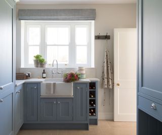 large utility room with back door and pale blue painted units and white butler sink