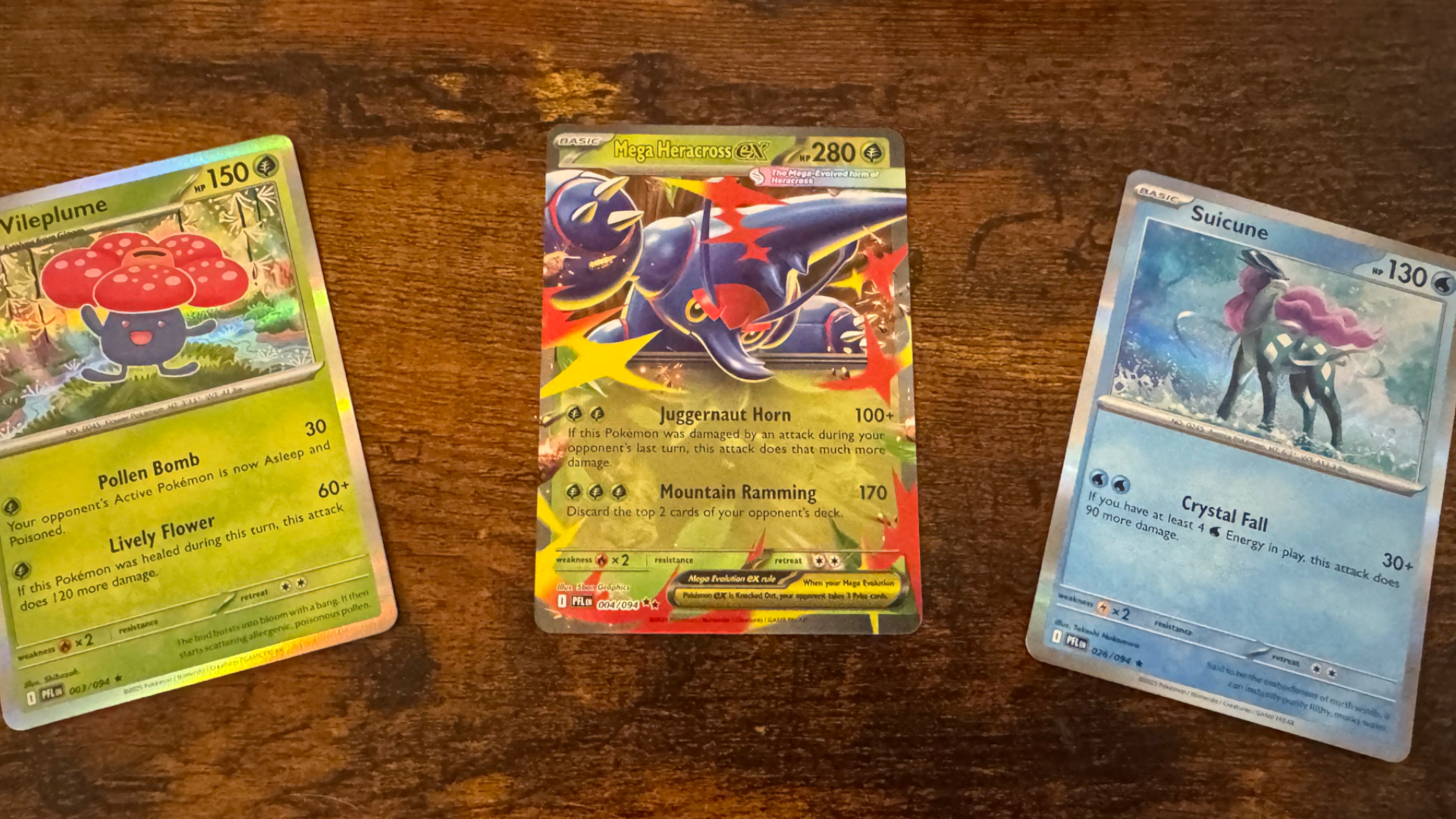 Three Pokemon Phantasmal Flames cards on a wooden background