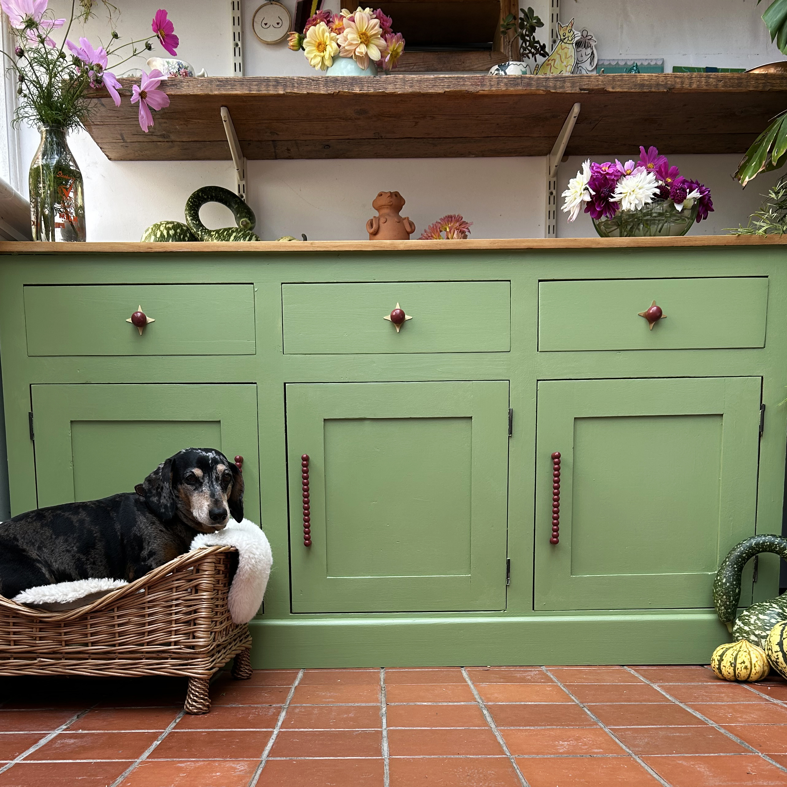 green cabinet with three drawers and a dog in a basket in front of it
