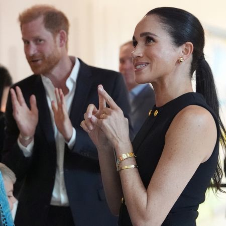 Meghan Markle talking to a group of girls next to Prince Harry