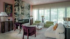 Living room with pink textured walls nad ceiling, green and white stone fireplace, white sofa, green armchairs and purple velvet armchairs
