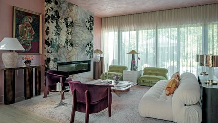 Living room with pink textured walls nad ceiling, green and white stone fireplace, white sofa, green armchairs and purple velvet armchairs