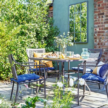 Dark grey table and chairs on patio with colourful cushions