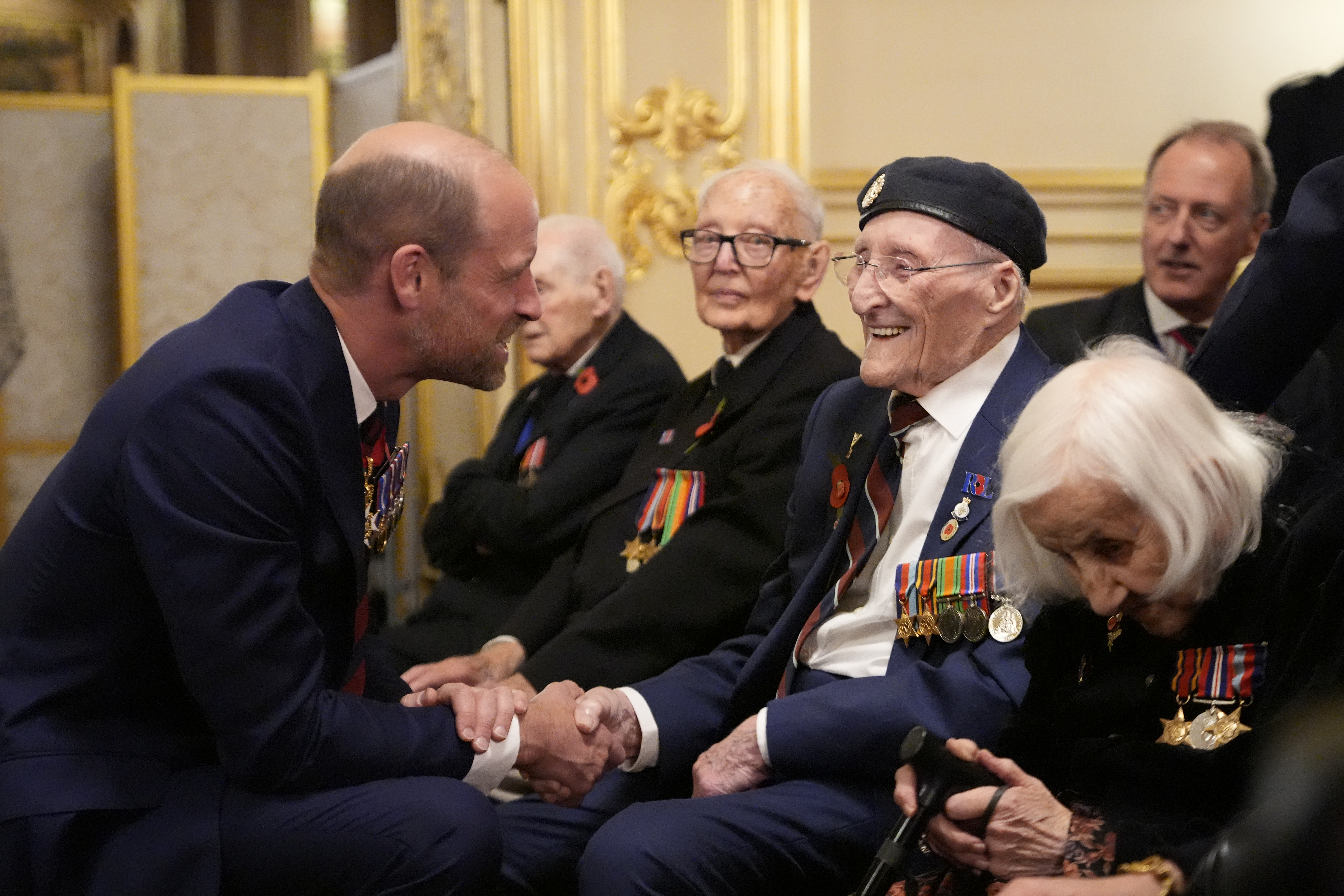 Prince William kneeling down shaking hands with a veteran