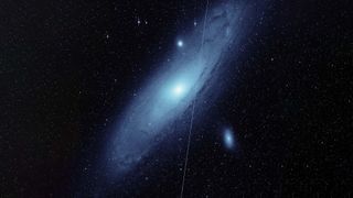 The Andromeda galaxy with a white line created by a Starlink satellite cutting across if from top to bottom.