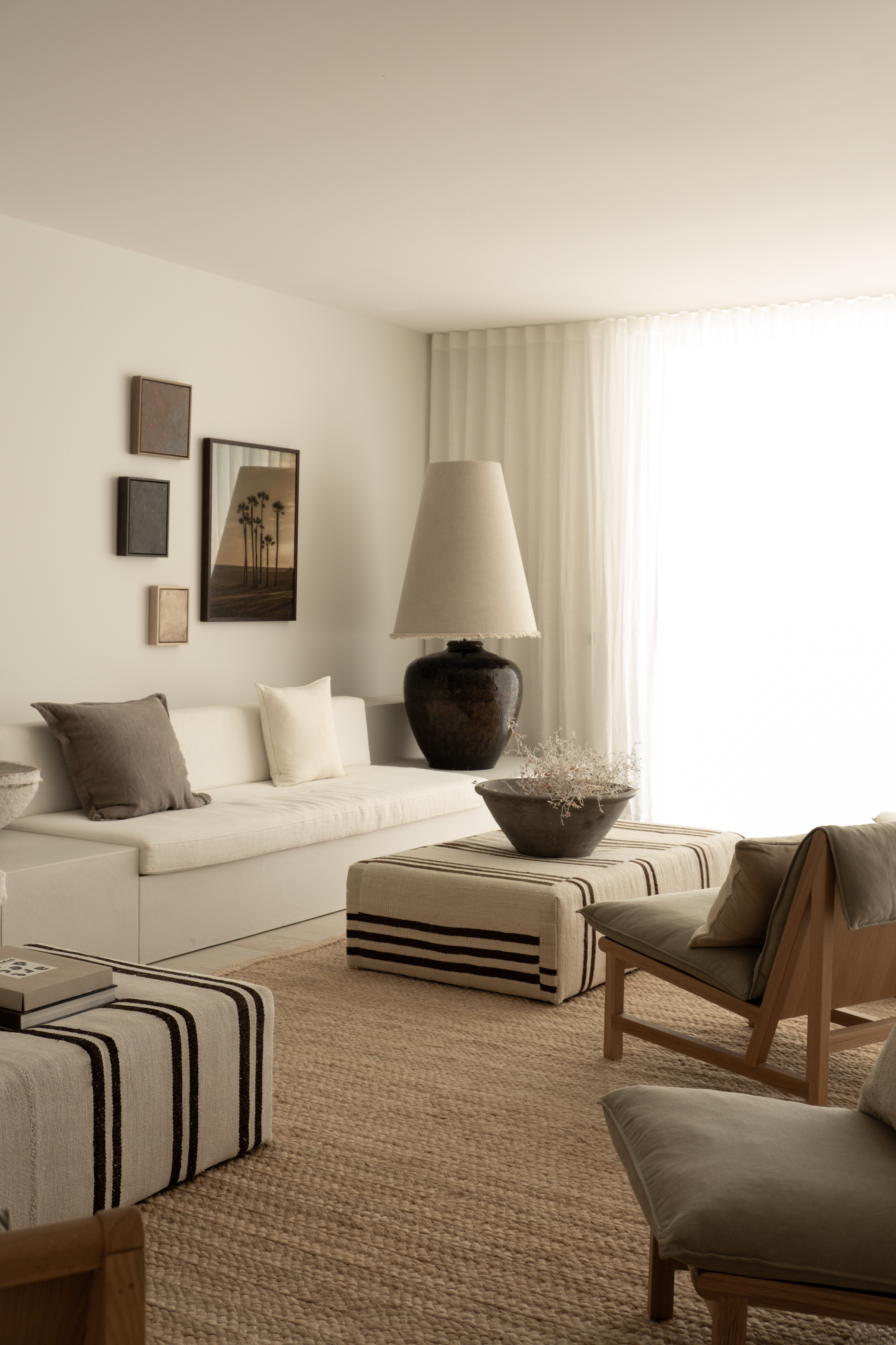 A living room with a beige rug, and warm white walls and seating