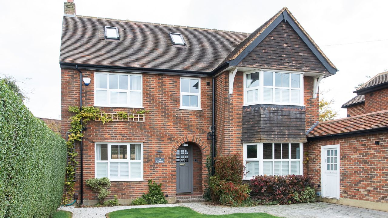 Exterior of a large detached house with a hedge one one side