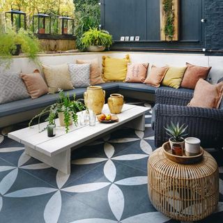 garden patio with patterned floor tiles and built in sofa with low level coffee table