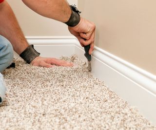person fitting and cutting carpet in a house
