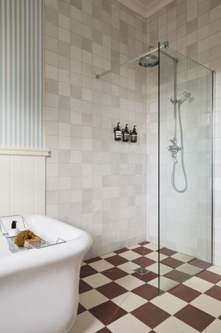 bathroom with white tub, blue and white stripe wallpaper, checked floor tiles, walk in shower