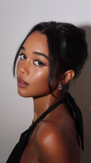 Laura Harrier with bun hairstyle with strands framing the face