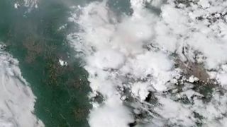 The McKinney wildfire as seen from space. Large white clouds can be seen forming from plumes of smoke on the ground in a satellite image.