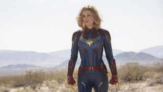 Captain Marvel står i sin uniform i en ørken