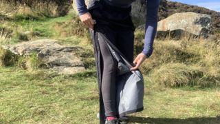 A hiker unzipping legs on rain pants