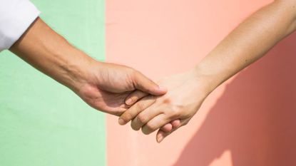 couple holding hands against a pink and green background
