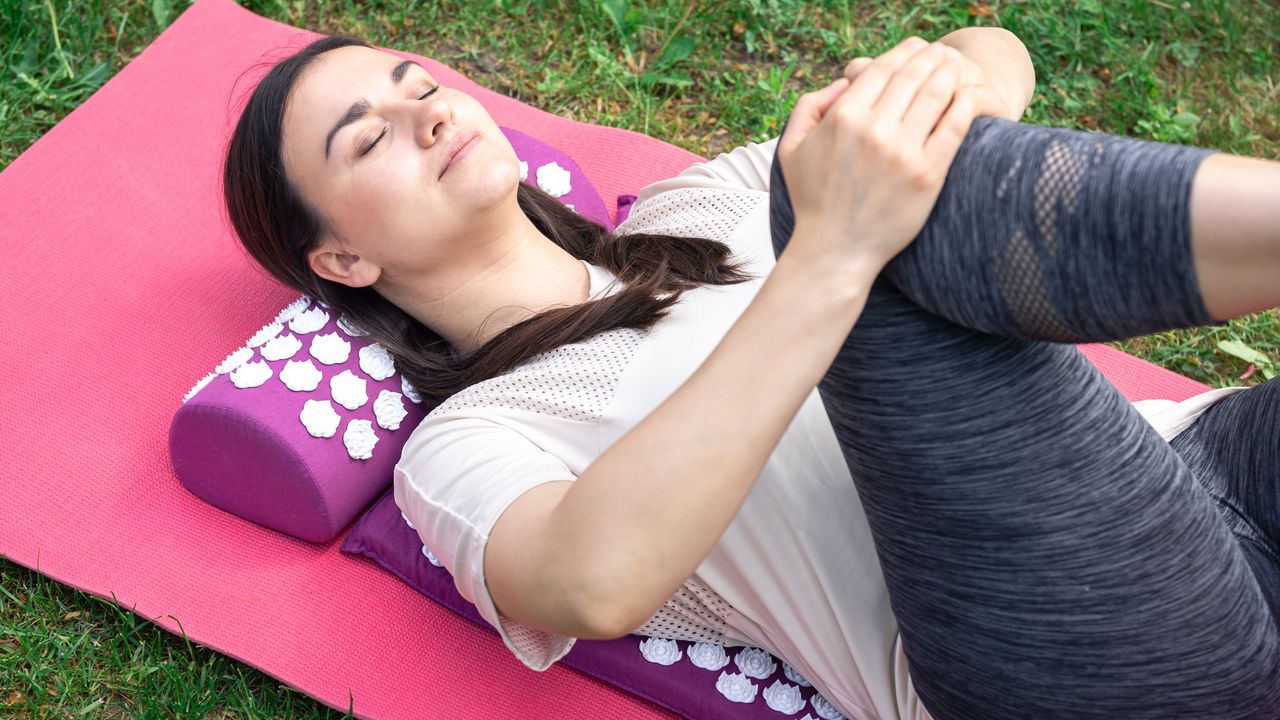 A woman stretches on an acupressure mat