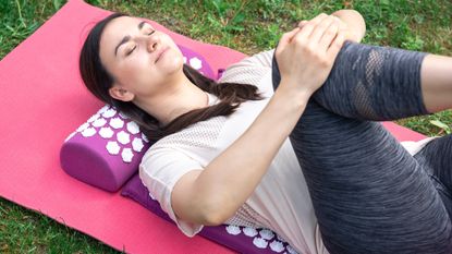 A woman stretches on an acupressure mat