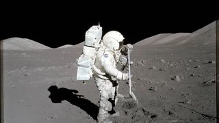 an astronaut on the moon holds a shovel, looking donward at the ground.