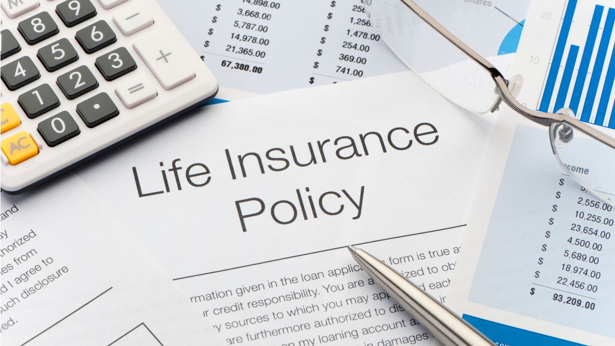 Life insurance policy documents on a desk next to a calculator and pen. 