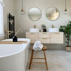japandi-style bathroom with white tub, double sink and micro cement wall