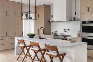 kitchen with pale wood floor and pale wood cabinets with white island white walls and black accessories and hanging shelf