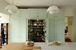 A classic English style pantry with light green cabinet doors