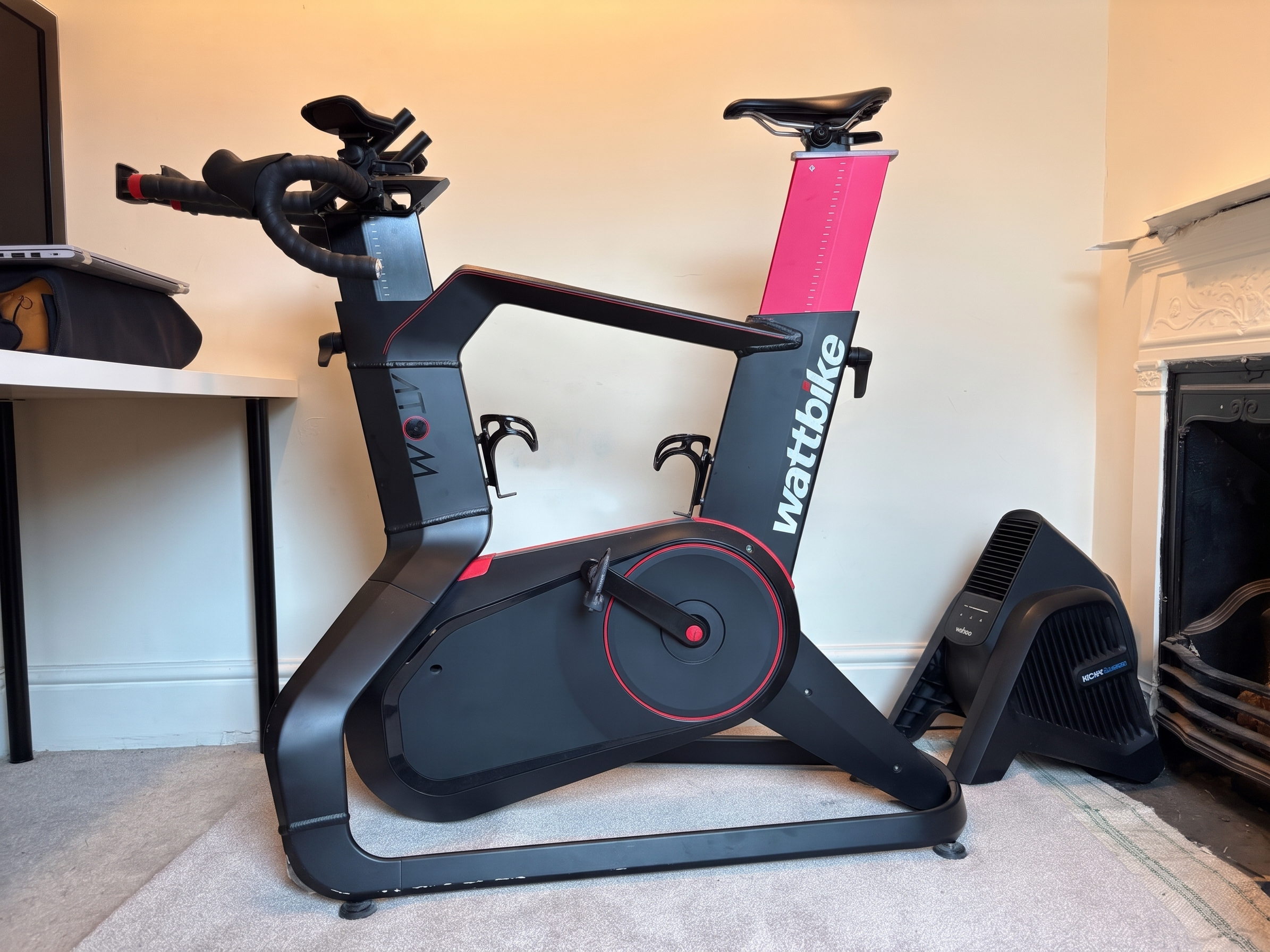 A black and red Wattbike Atom smart bike sits in front of a TV