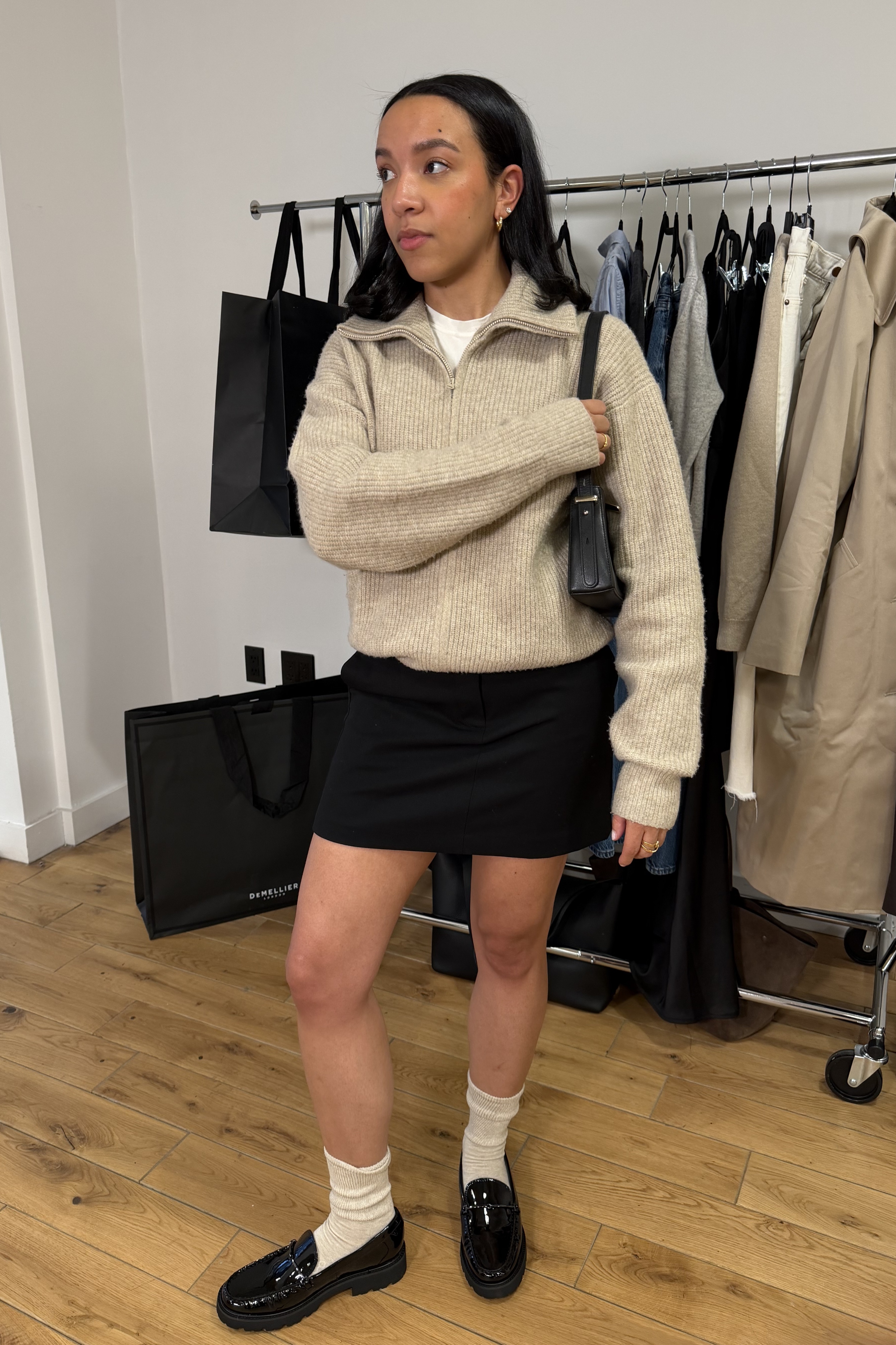 Lauren Tappan wearing a sweater, a tee, a skirt, loafers and socks