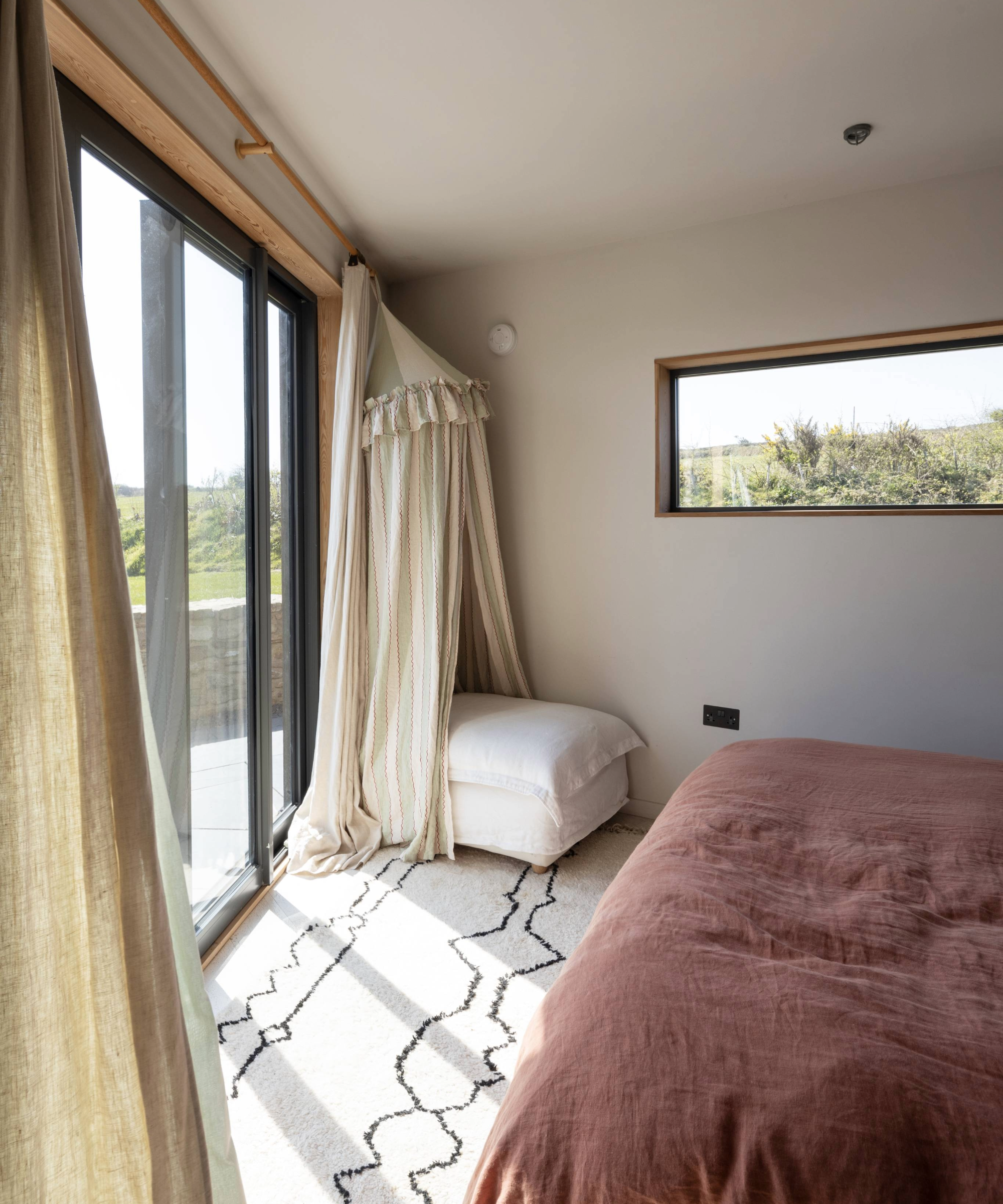 Bedroom with large patio doors to the left and small rectangle window on front facing wall