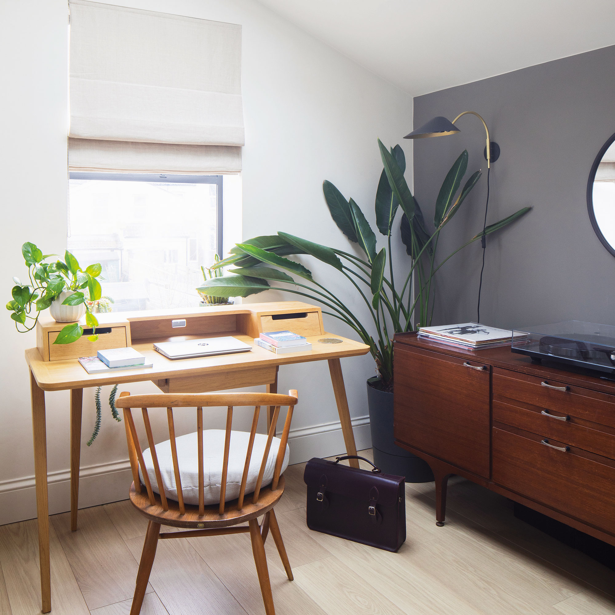 Navy and white home office with wooden desk and spindle chair, with a mid-century style sideboard