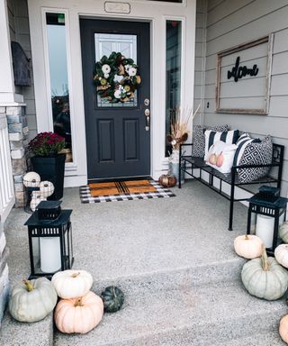 Front porch with layered patterns, lanterns, wreath and neutral pumpkins - MC Rustic Home