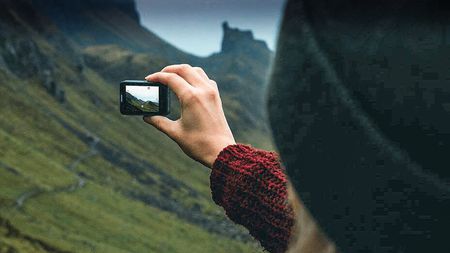 Man holding an Akaso EK7000 Pro action camera to video a dramatic landscape