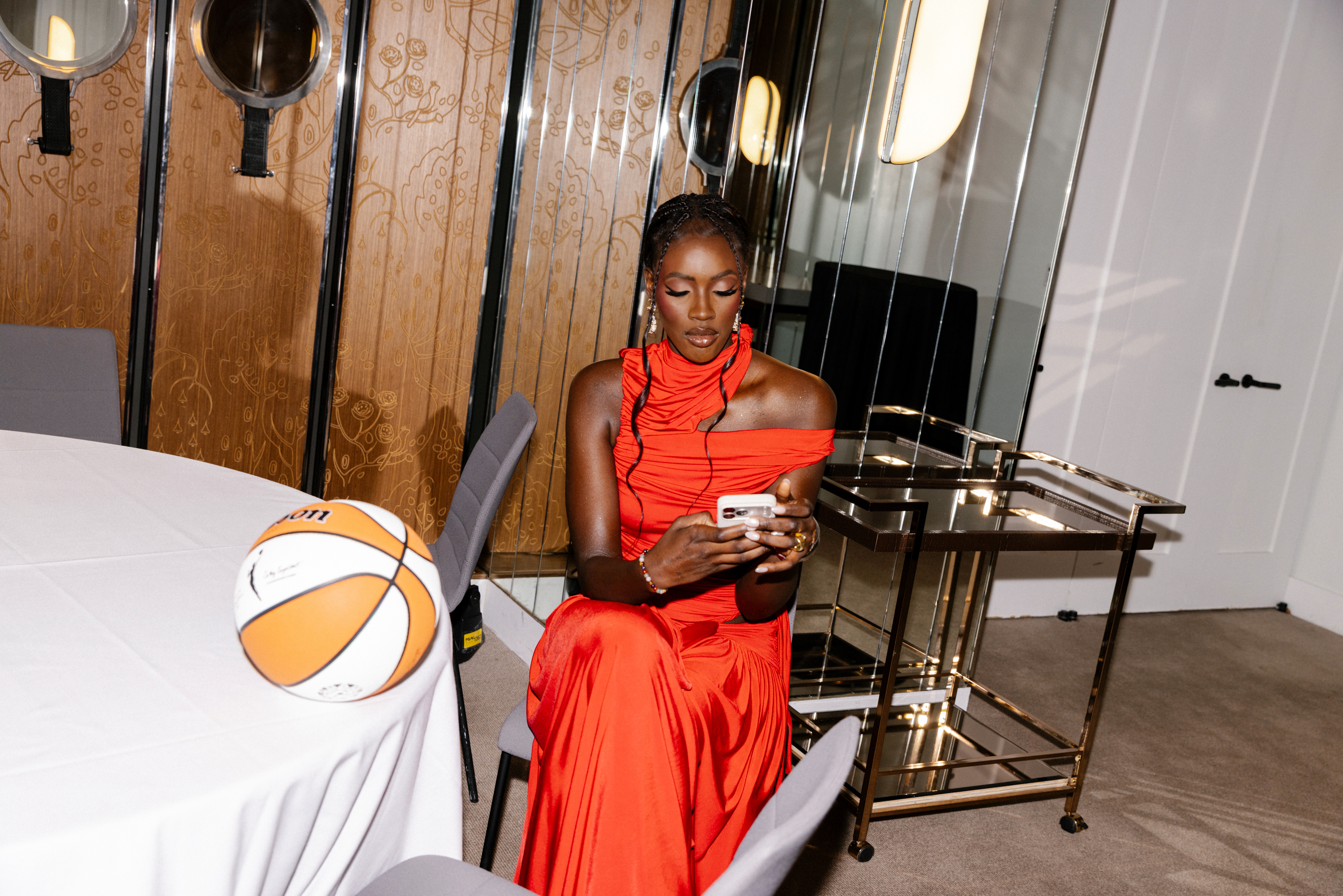 Awa Fam getting ready for the 2026 WNBA Draft with stylist Courtney Mays wearing a red Siedres dress from Shopbop.