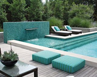 A bright blue mosaic tile pool with gray wood deck