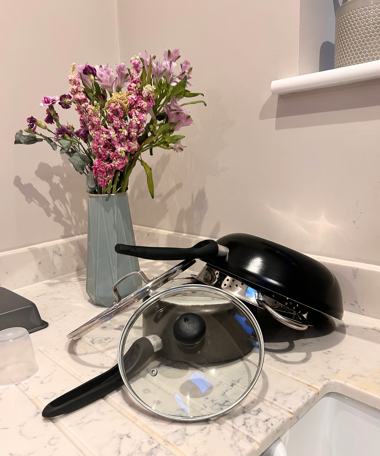 Before - pots and pans left out to dry on kitchen worktop with flowers in a vase.