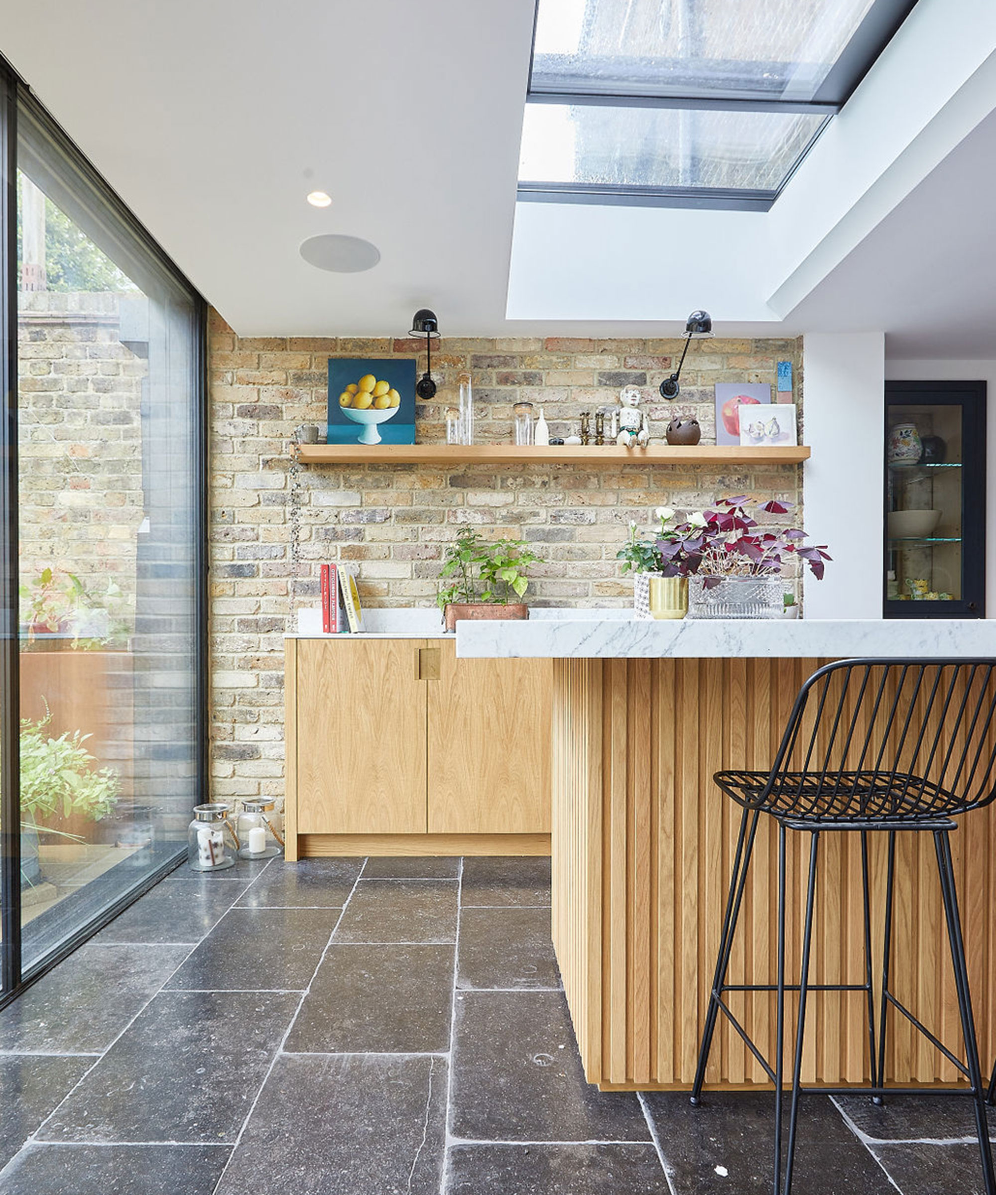 modern wooden kitchen with fluted cabinets and exposed brick wall and slate flooring