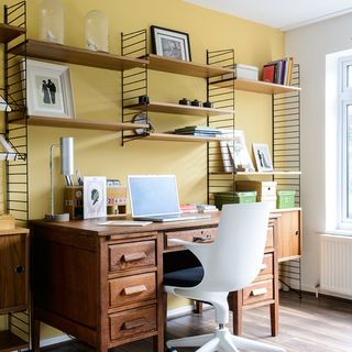 home office with yellow wall and shelves and desk and white chairs