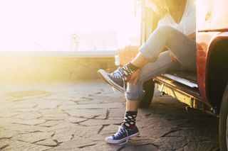 A person pulling on Vans shoes while sitting in the back of their camper van