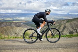 Image shows cyclist riding the Pinarello X road bike in a black paint scheme