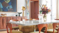 a dining room wiht a brass and marble table and interesting art sculptures