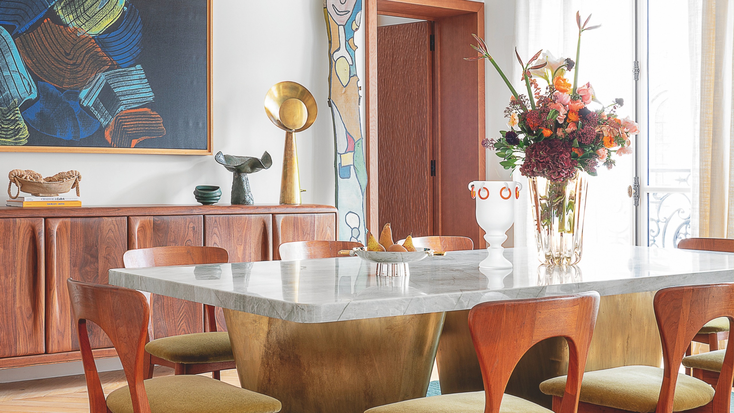 a dining room wiht a brass and marble table and interesting art sculptures