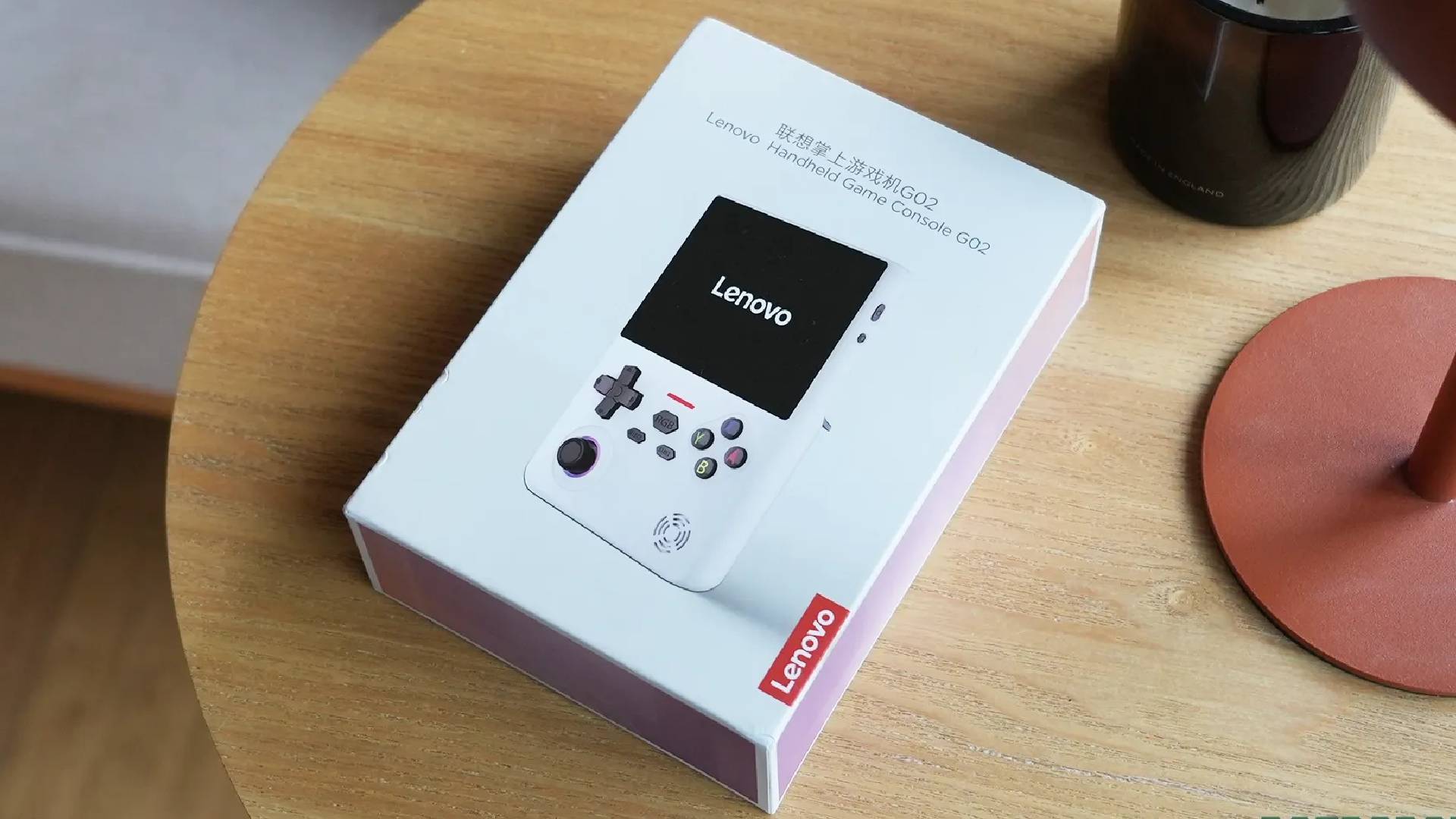 White Lenovo G02 handheld box on woodgrain side table.