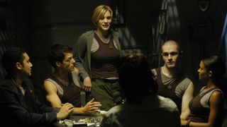 Six characters from the TV show "Battlestar Galactica" sit around a small circular table