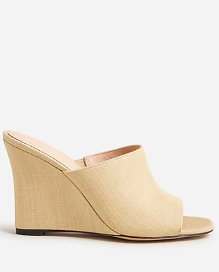 a pair of straw wedge sandals by j.crew in front of a plain backdrop