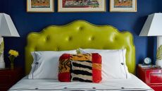Navy blue bedroom featuring a bed with a chartreuse tufted leather headboard.
