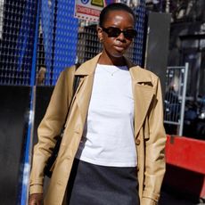 Sylvie Mus during Paris Fashion Week wearing a trench coat, white boatneck tee, and miniskirt. 